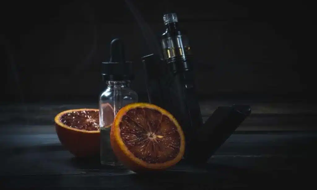 Juice feito em casa, após aprender a fazer o seu próprio juice, laranjas e vape sobre uma mesa